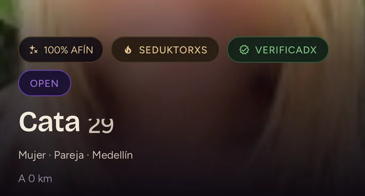 Ficha de un perfil en la app: la cara sale difuminada, con la insignia de 100 % de afinidad, el sello de verificadx y los botones de descartar y "Te gusta".